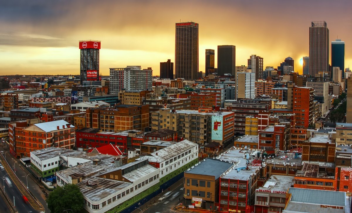 A panoramic view of Johannesburg's cityscape at sunset, highlighting the tall buildings and urban landscape.