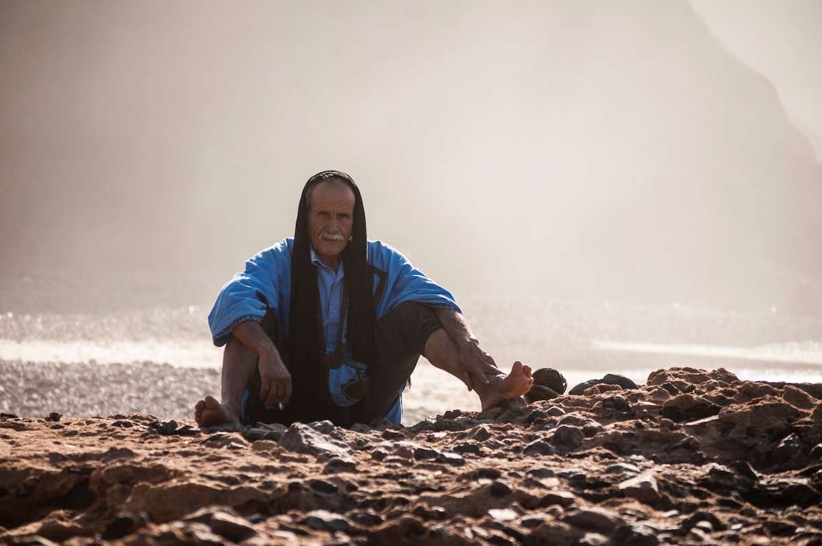A local man sits on the pebbles on Legzira Beach in Morocco