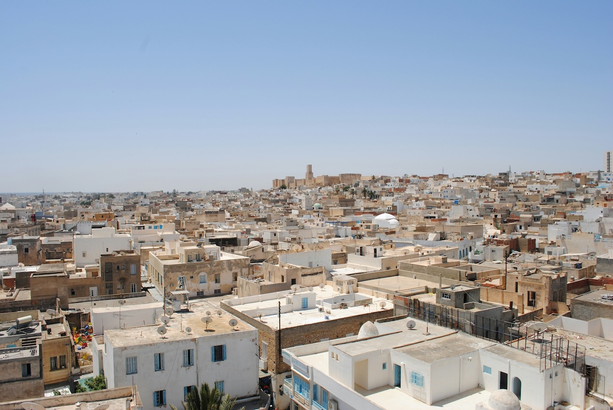 A panoramic view of the Medina in Tunisia, showcasing a dense array of traditional white buildings with flat roofs under a clear sky.