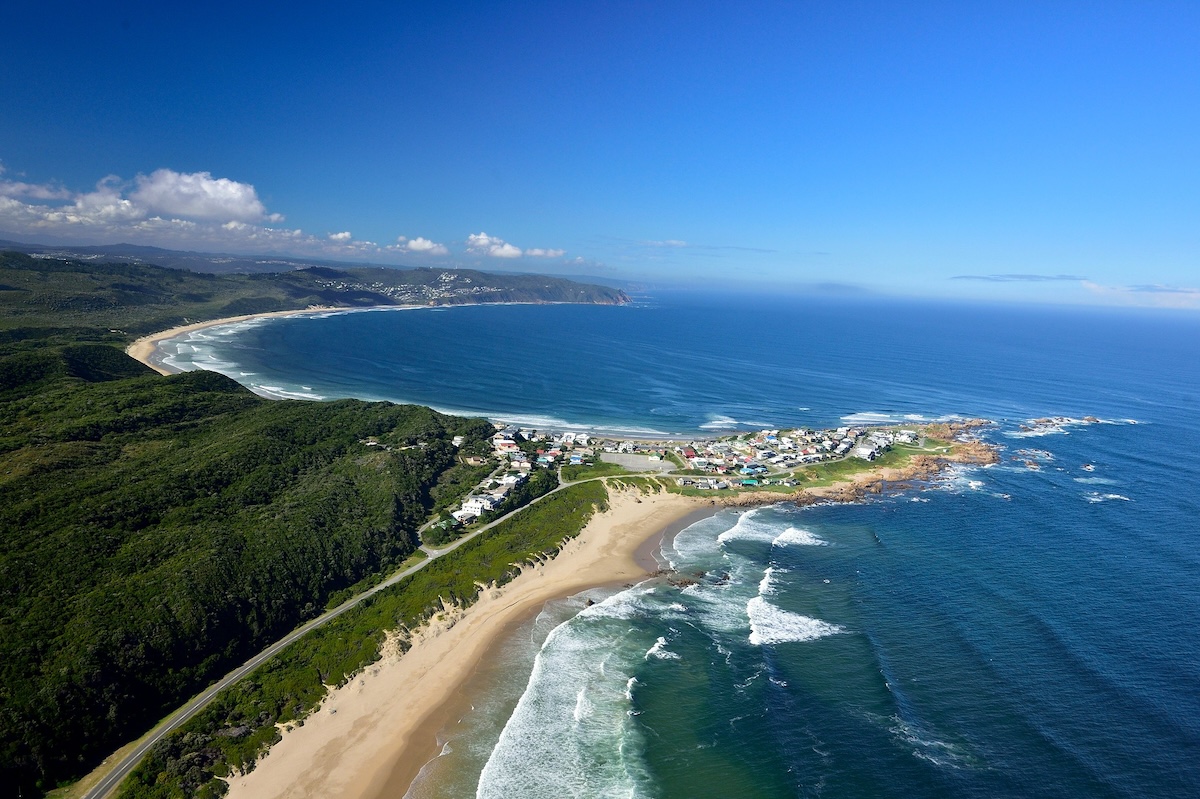 An aerial view of the Garden Route coastline with winding beaches, small coastal towns, and dense greenery.